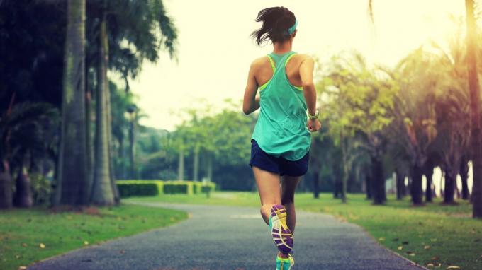 אורח חיים בריא צעירה אסייתית ספורטיבית רצה בפארק טרופי